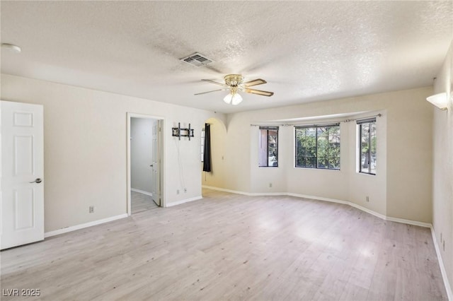 spare room featuring light wood-type flooring, ceiling fan, and a textured ceiling