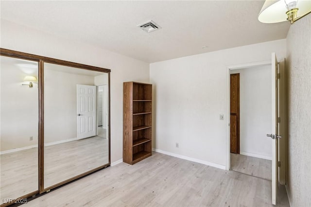 unfurnished bedroom with light wood-type flooring and a closet