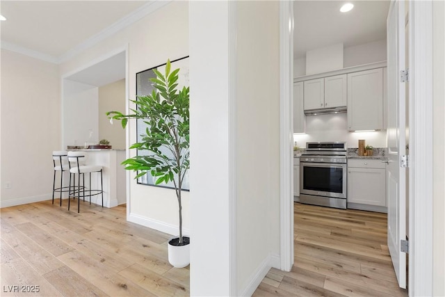 kitchen with crown molding, stainless steel range, white cabinets, and light hardwood / wood-style floors