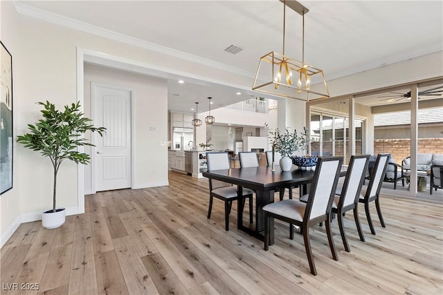 dining space featuring a notable chandelier, light wood-type flooring, and crown molding