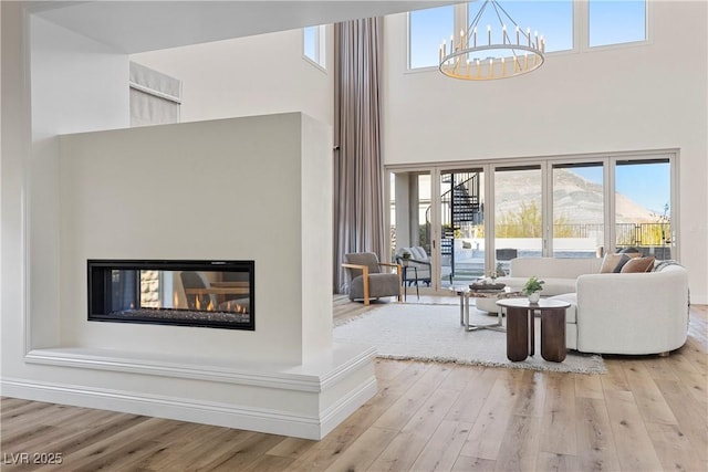 living room featuring a mountain view, light hardwood / wood-style flooring, a healthy amount of sunlight, and a notable chandelier