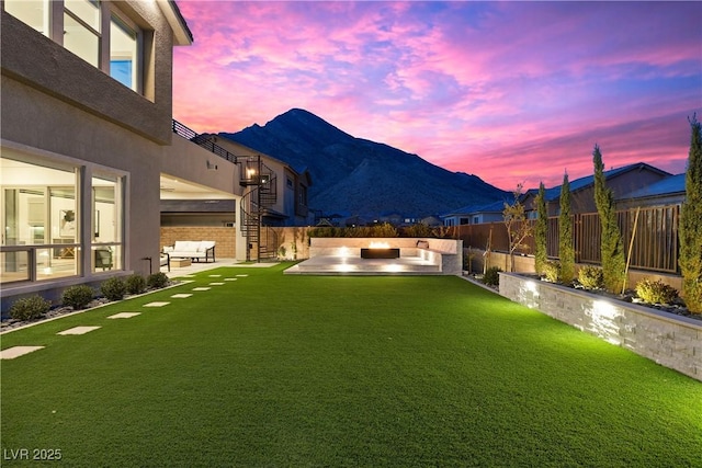 yard at dusk with a patio area, a mountain view, and an outdoor living space