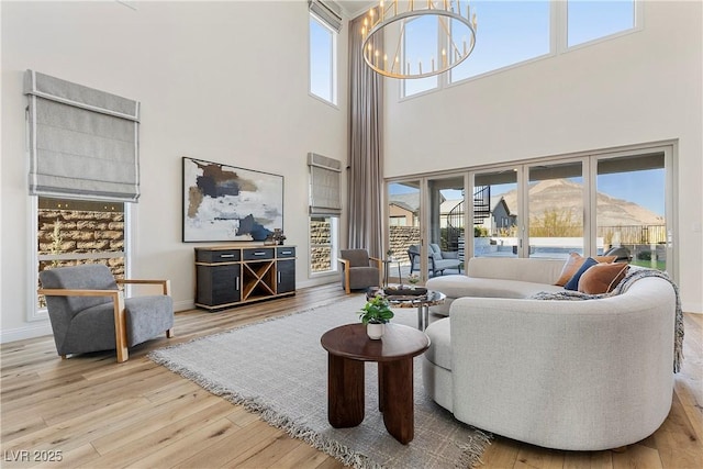 living room featuring a mountain view, a high ceiling, light hardwood / wood-style floors, and a notable chandelier