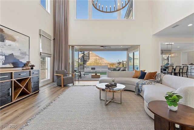 living room with plenty of natural light, a towering ceiling, and ceiling fan with notable chandelier