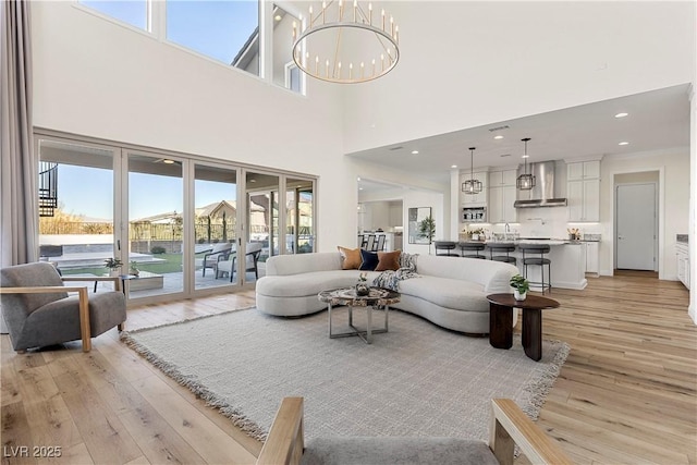 living room with a chandelier, a towering ceiling, and light hardwood / wood-style floors