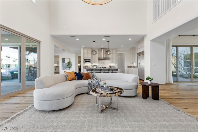 living room with light wood-type flooring and a towering ceiling