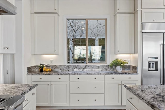 kitchen featuring light stone counters, stainless steel built in fridge, and white cabinets