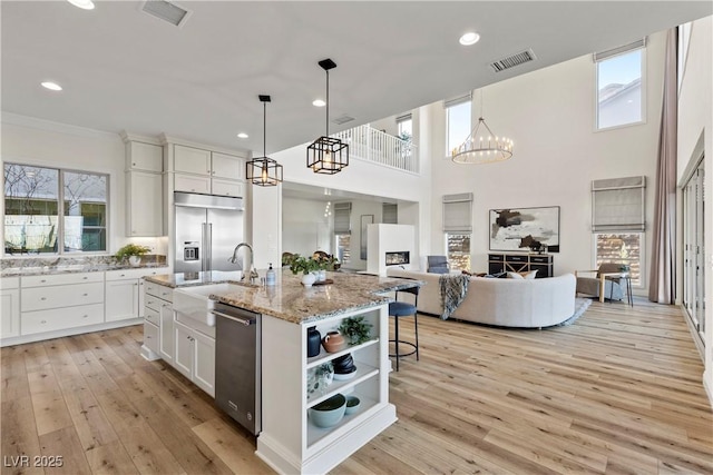 kitchen with white cabinets, pendant lighting, an island with sink, and appliances with stainless steel finishes