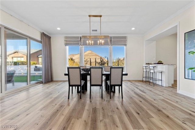 dining space featuring a mountain view, light hardwood / wood-style floors, crown molding, and a healthy amount of sunlight