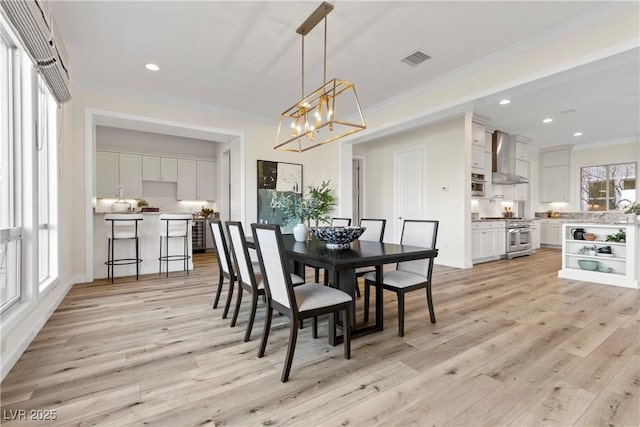 dining room featuring a wealth of natural light, crown molding, and light wood-type flooring