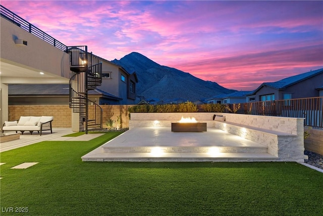 yard at dusk featuring a mountain view, a patio area, and an outdoor living space with a fire pit