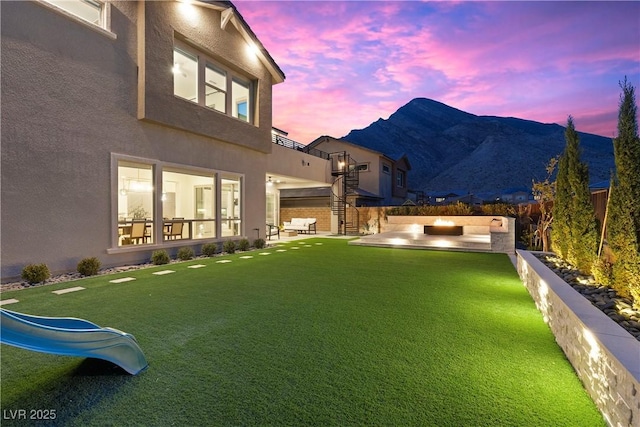 yard at dusk featuring a mountain view and a patio area