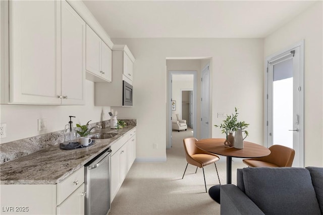 kitchen featuring light carpet, light stone counters, stainless steel appliances, sink, and white cabinets