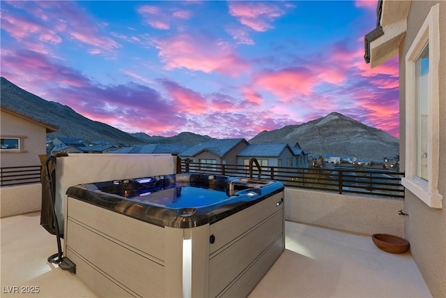 patio terrace at dusk featuring a mountain view and a hot tub