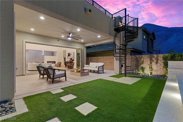 yard at dusk with ceiling fan, an outdoor hangout area, and a patio