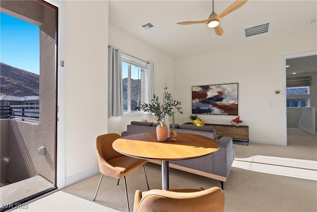 carpeted dining area featuring a mountain view and ceiling fan