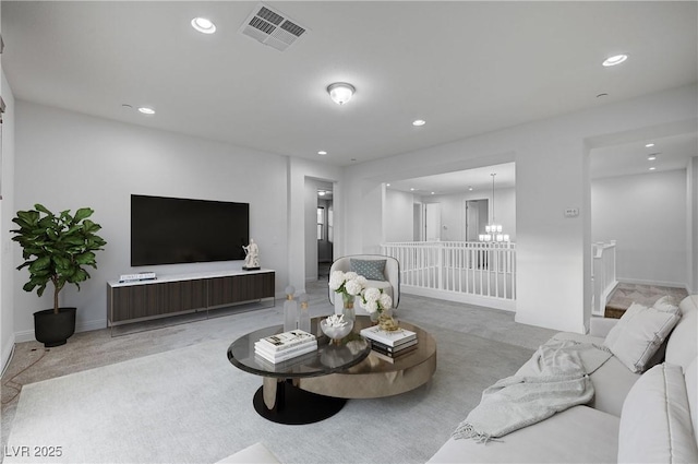 carpeted living area with a notable chandelier, recessed lighting, visible vents, and baseboards