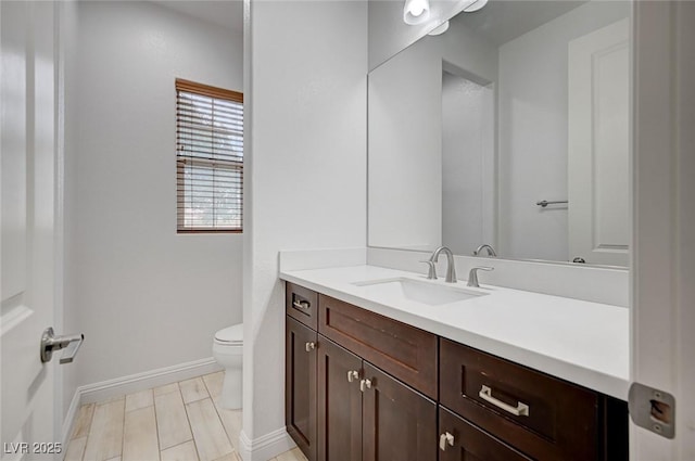 bathroom with toilet, vanity, and baseboards