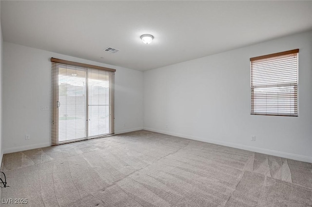 unfurnished room featuring carpet, visible vents, a wealth of natural light, and baseboards