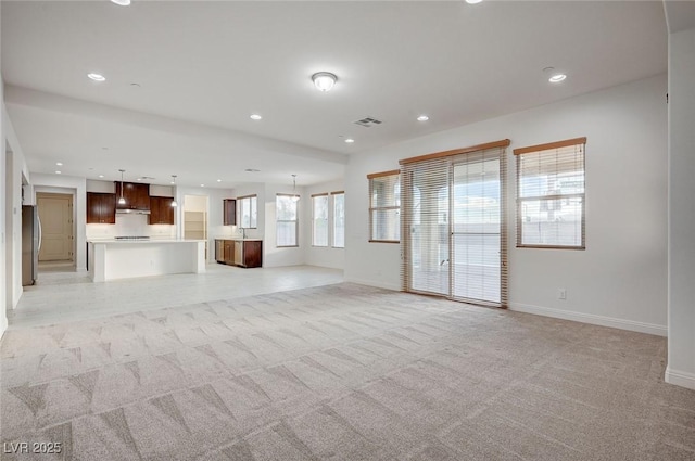 unfurnished living room with visible vents, recessed lighting, light colored carpet, and baseboards