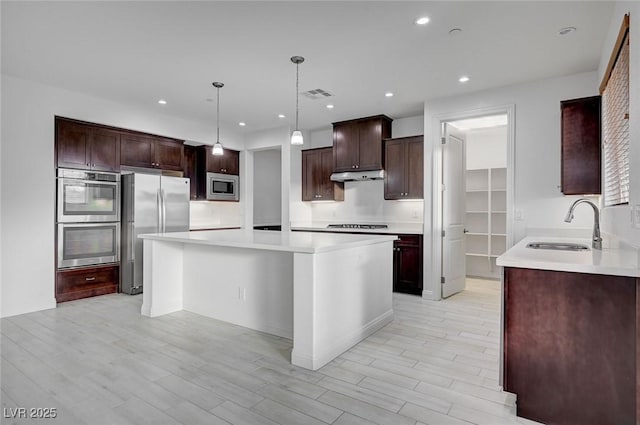 kitchen featuring visible vents, a sink, under cabinet range hood, appliances with stainless steel finishes, and light countertops