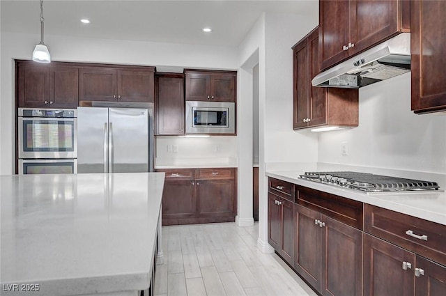 kitchen featuring under cabinet range hood, light countertops, recessed lighting, hanging light fixtures, and stainless steel appliances