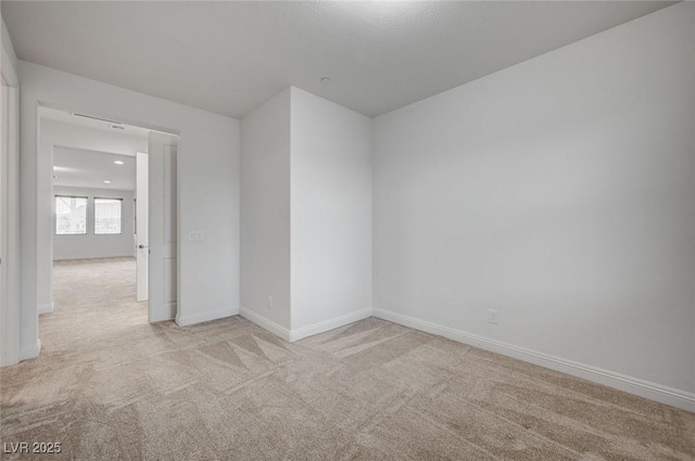 spare room with light carpet and baseboards