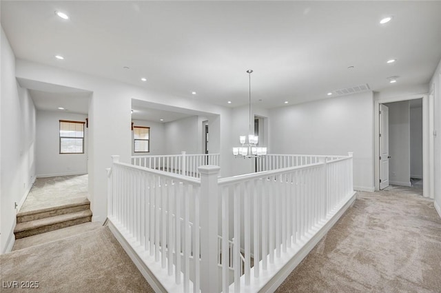 corridor featuring visible vents, a notable chandelier, recessed lighting, carpet floors, and baseboards