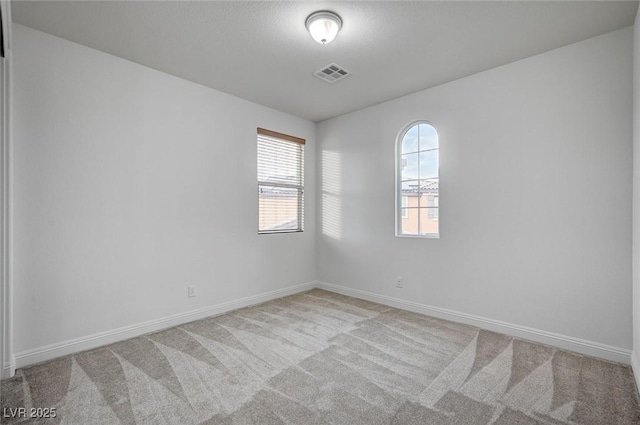 empty room featuring carpet, visible vents, and baseboards