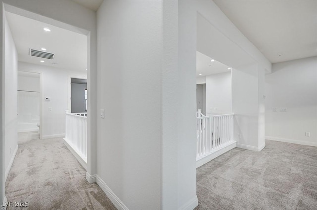 hall featuring visible vents, baseboards, and carpet floors