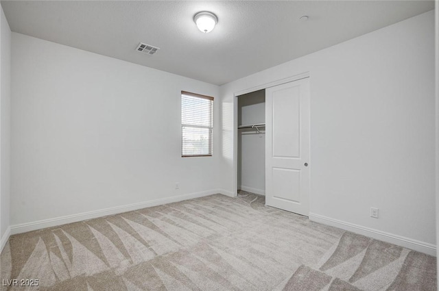 unfurnished bedroom with baseboards, visible vents, carpet floors, and a closet