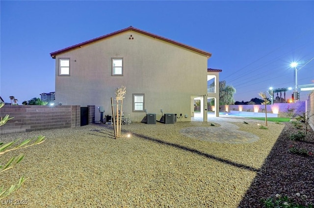 back of house featuring central AC unit, a fenced backyard, a fenced in pool, and stucco siding