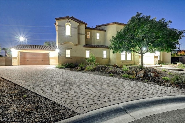 view of front of home with decorative driveway, a tile roof, and stucco siding