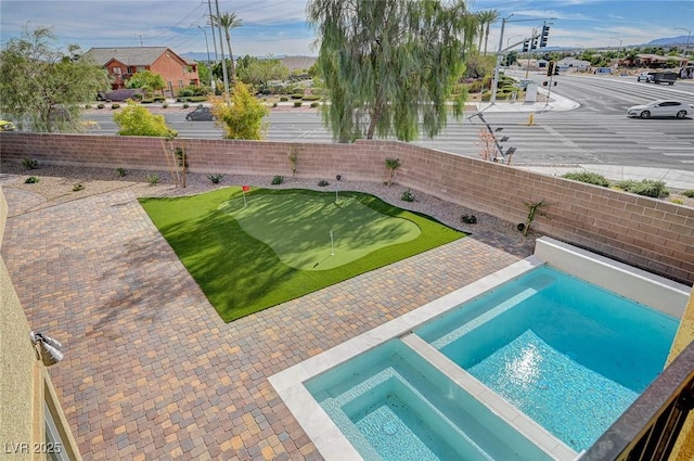 view of swimming pool featuring a fenced backyard and a pool with connected hot tub