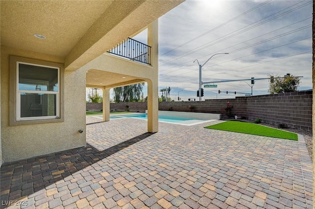 view of patio featuring a balcony, a fenced backyard, and a fenced in pool