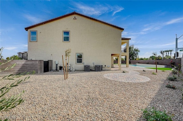 rear view of house with stucco siding, a balcony, a fenced backyard, and a patio area