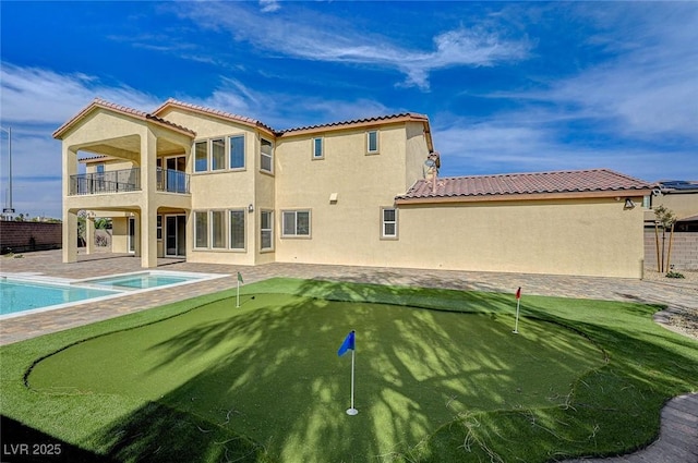 back of property with stucco siding, a patio area, a fenced in pool, a balcony, and a hot tub