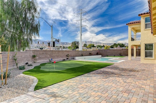 exterior space featuring a fenced backyard, a fenced in pool, a mountain view, and a patio