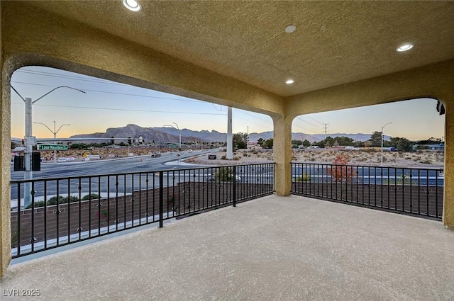 patio terrace at dusk featuring a mountain view and a balcony