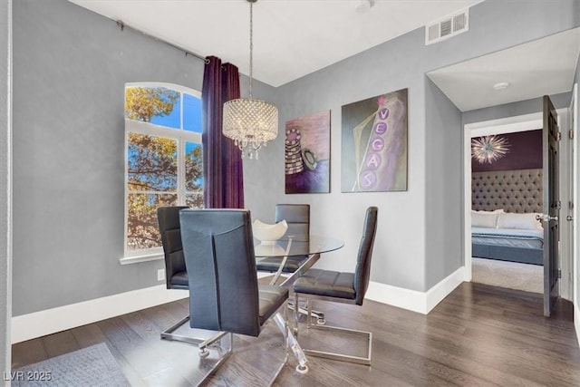 dining room with dark hardwood / wood-style floors, a wealth of natural light, and a notable chandelier