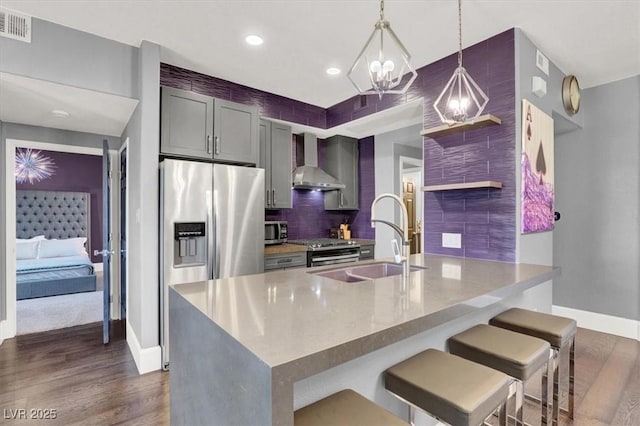 kitchen featuring sink, wall chimney range hood, pendant lighting, stainless steel appliances, and backsplash