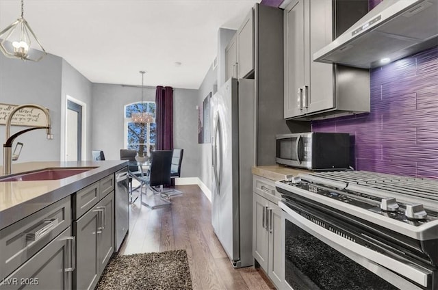 kitchen featuring gray cabinets, pendant lighting, and wall chimney range hood