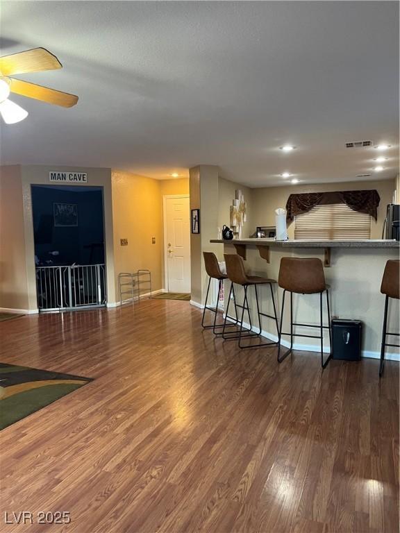 bar with ceiling fan and dark hardwood / wood-style flooring