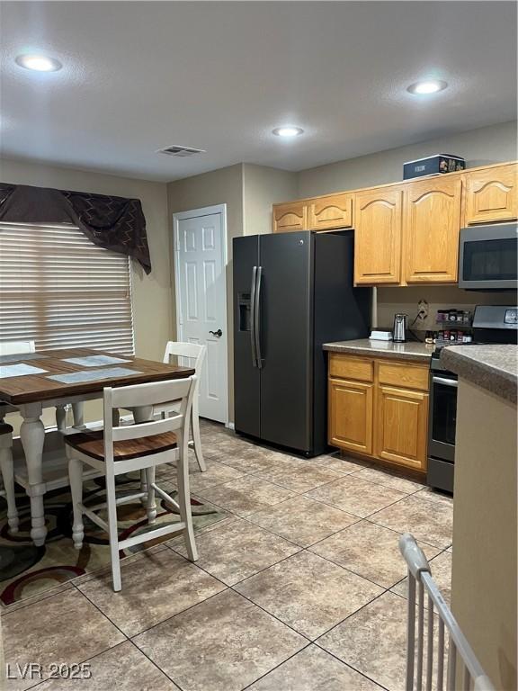 kitchen featuring light brown cabinetry, light tile patterned floors, and stainless steel appliances