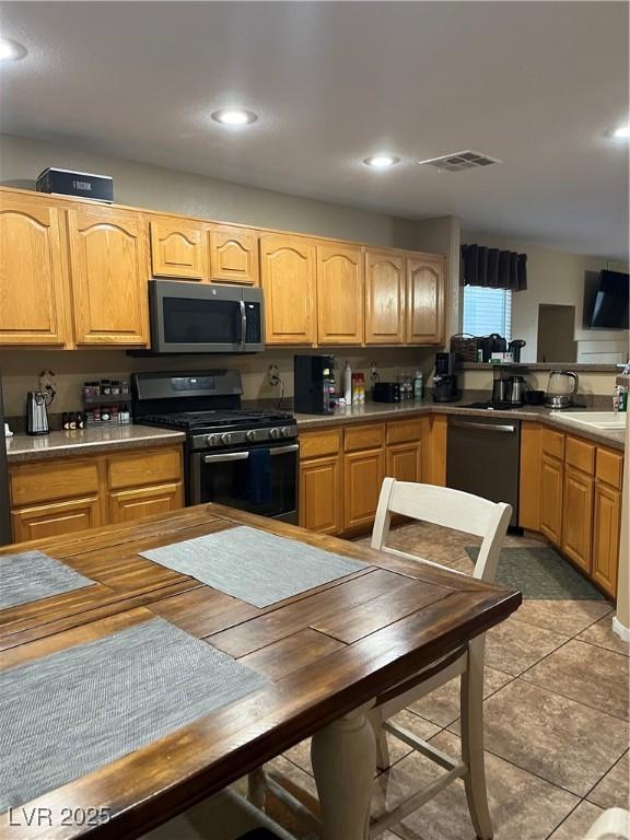 kitchen with sink, dishwasher, black gas stove, and light tile patterned floors