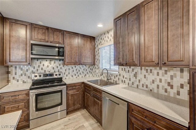 kitchen featuring backsplash, sink, stainless steel appliances, and light hardwood / wood-style flooring