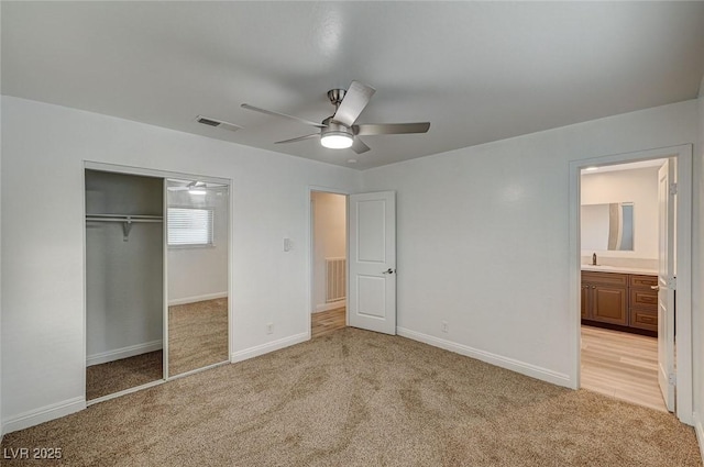 unfurnished bedroom with ceiling fan, light colored carpet, connected bathroom, and a closet