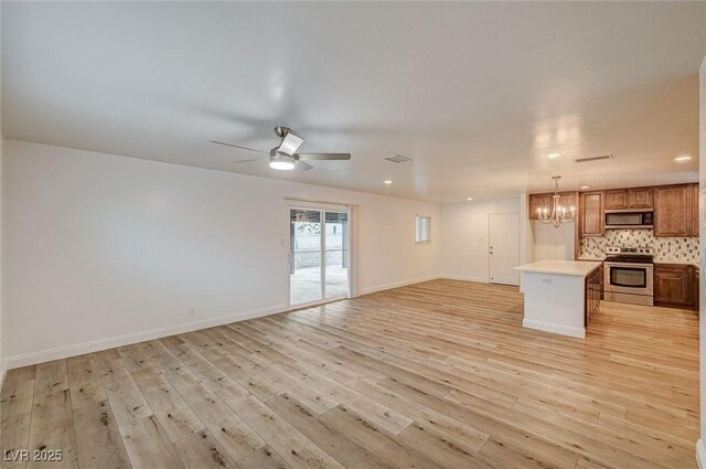 unfurnished living room with ceiling fan with notable chandelier and light wood-type flooring