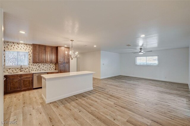 kitchen with tasteful backsplash, stainless steel dishwasher, sink, decorative light fixtures, and a center island