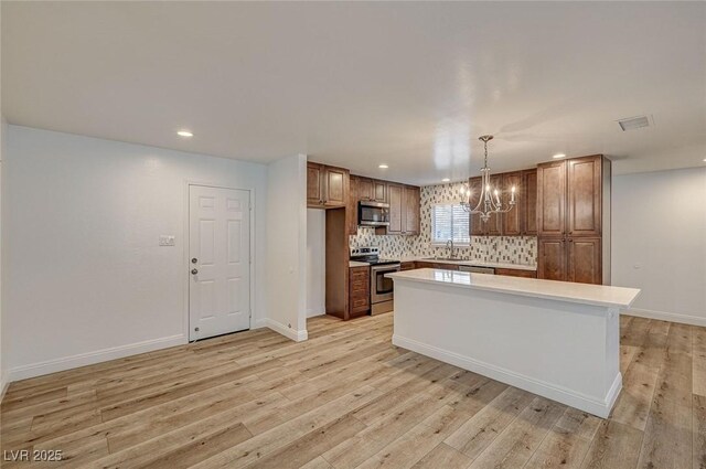 kitchen featuring a center island, sink, appliances with stainless steel finishes, decorative light fixtures, and a chandelier